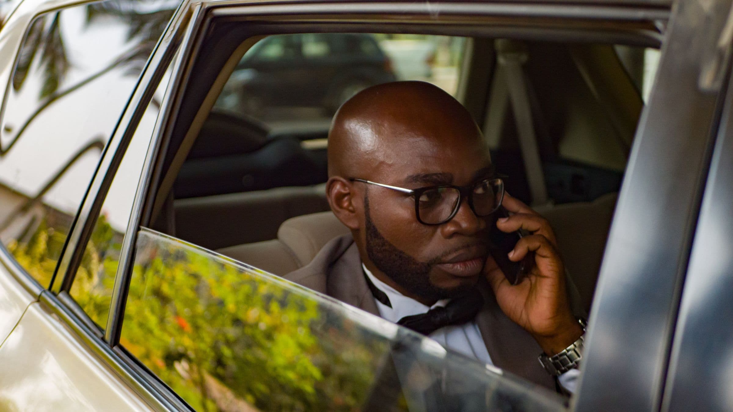 Executive in a suit taking a call in the back seat of a car