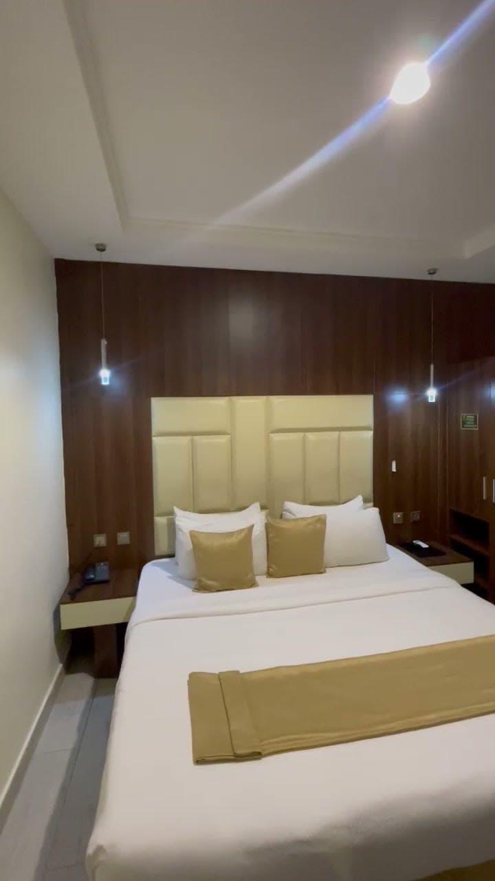 King-size bed with gold cushions against a padded headboard and wood-panelled wall
