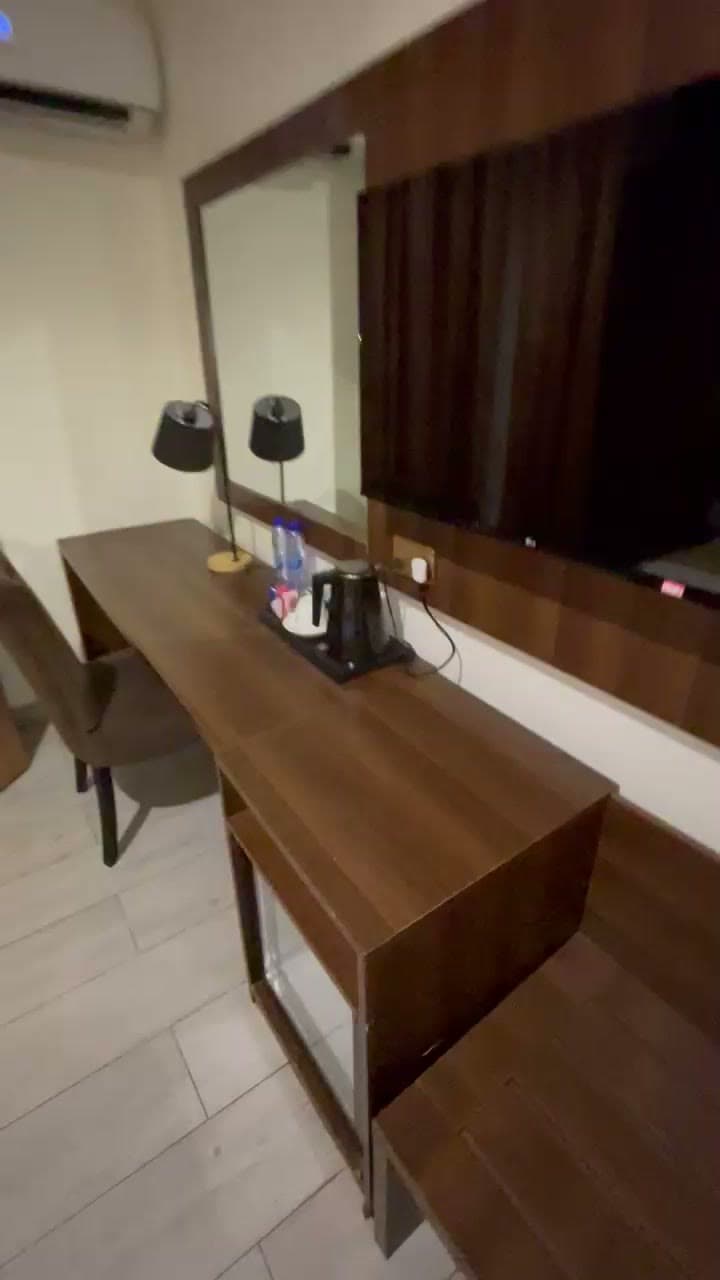 Wooden work desk with two lamps, a kettle, a tea tray and bottled water