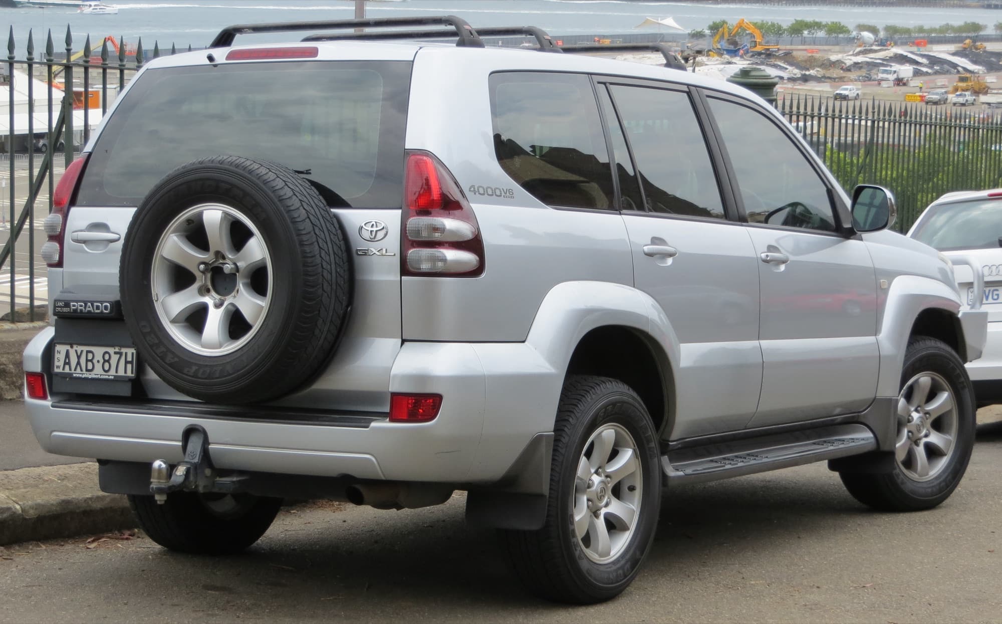 Silver Toyota Land Cruiser Prado parked beside a harbour fence